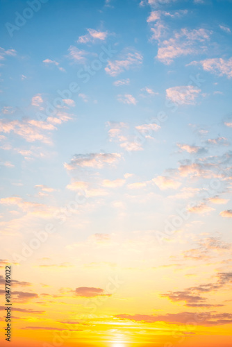 Sunset or sunrise sky with a vibrant gradient of orange, gold, and soft blue. Clear atmosphere with wispy clouds. Peaceful, natural light background. hope, freedom, new day Concepts, Vertical