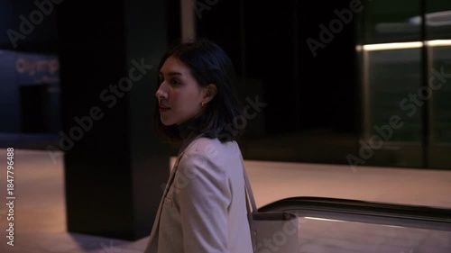 Elegant businesswoman riding down escalator in modern building