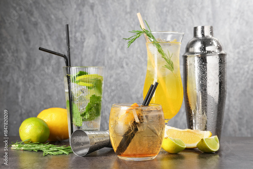 Glasses of tasty cocktails, ingredients, shaker and jigger on grey table