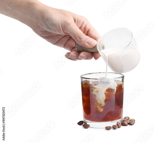 Woman pouring milk into iced coffee on white background, closeup
