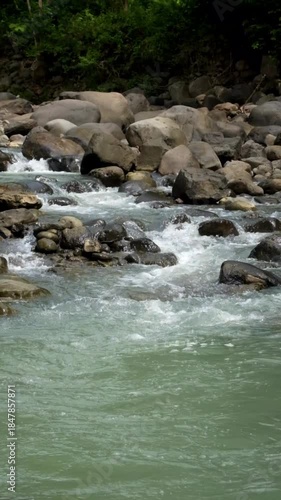 Vertical video of a rocky river flowing in the mountains. A clear waterfall. A peaceful and calm atmosphere for relaxation. Ecological and environmental concepts. Real-time footage, 4K