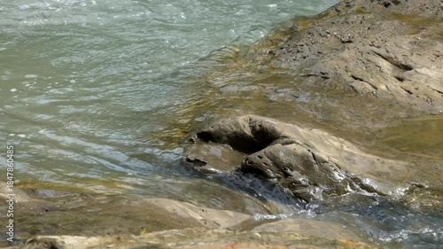 River flowing through the crevices of river rocks. Peaceful and calm atmosphere for relaxation. Ecological and environmental concept. Realtime footage, 4K