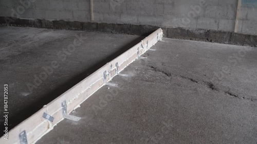 Freshly poured concrete screed floor drying and curing on a construction site. Cracks appearing in the wet mixture over time