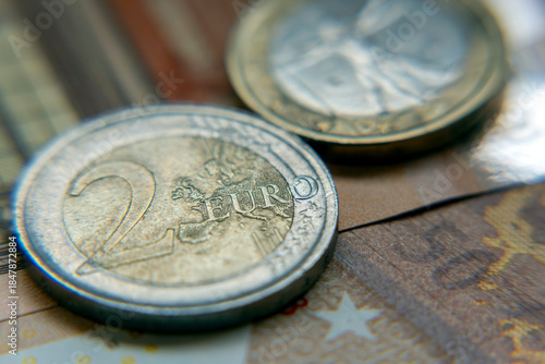 Close view of a two euro coin beside euro banknotes on a patterned surface showing details and textures