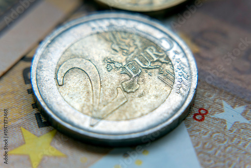 Close up of two euro coin on banknotes showing details and numbering during bright daylight