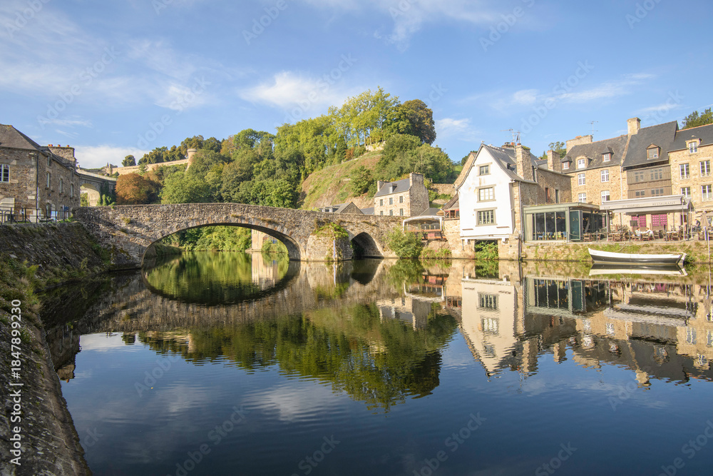 Fototapeta premium Le vieux port et vieux pont de Dinan en Bretagne et ses reflets sur la riviere de la Rance en été, departement des Côtes d'Armor