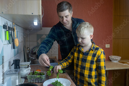 Father and son preparing a meal together in a kitchen. Parent teaching a child everyday skills, shared activity, healthy food habits, warm bonding moment, natural lifestyle scene.