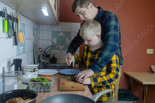 Father and son preparing a meal together in a kitchen. Parent teaching a child everyday skills, shared activity, healthy food habits, warm bonding moment, natural lifestyle scene.