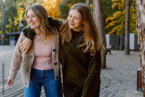 Foto Two friends walk closely together on a sandy path surrounded by tall trees