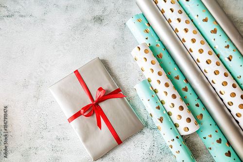Wallpaper Mural Flat lay of gift wrapped in silver paper with red ribbon and rolls of stylish wrapping paper. Festive mood, minimal and modern holiday vibe Torontodigital.ca