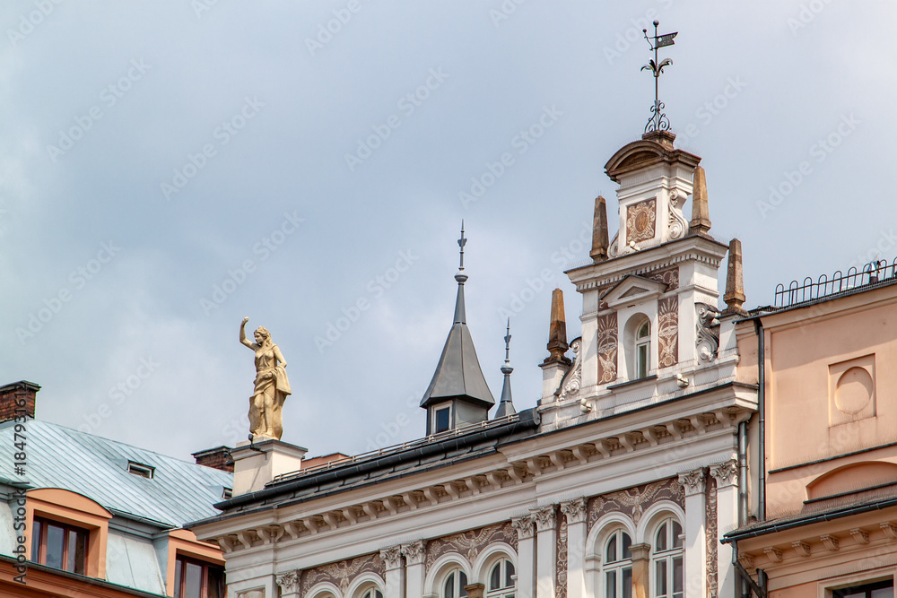 Obraz premium Ornate historical building facade with architectural statues and intricate detailing against cloudy sky, showcasing European urban architecture and decorative elements