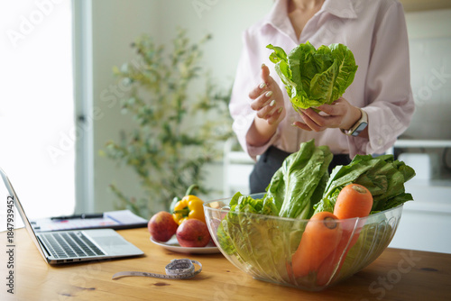 Health consultant selecting fresh lettuce during an online consultation or meal prep session. Concept of telehealth, and remote wellness.