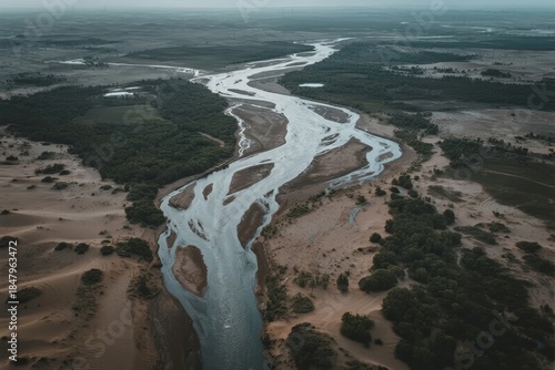 Fototapeta Naklejka Na Ścianę i Meble -  Aerial view of a winding river cutting through desert and green vegetation
