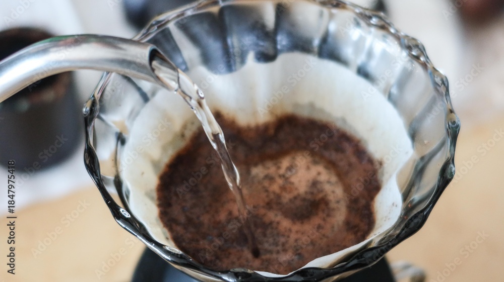Fototapeta premium close up of adding hot water to make hand brewed pour over coffee to the filter paper in a transparent pour over filter 