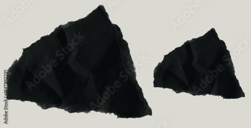 Two ripped pieces of black paper on gray