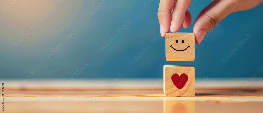 Naklejka premium Employee satisfaction and wellbeing concept with a hand selecting a wooden block with smiling heart symbol, representing care, engagement, motivation, and positive workplace culture.