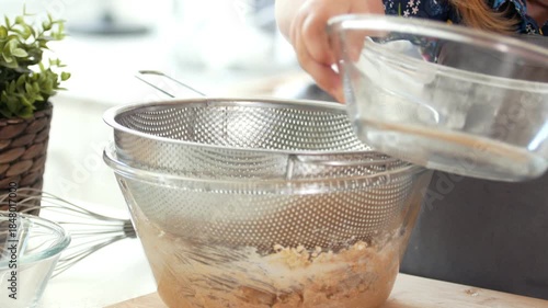 Little girl baker sifts flour through a sieve