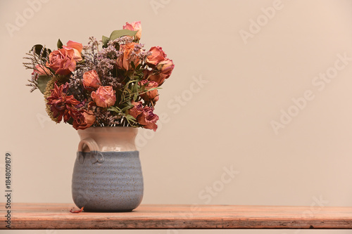 a bouquet of dried roses and wildflowers arranged in a handmade ceramic vase
