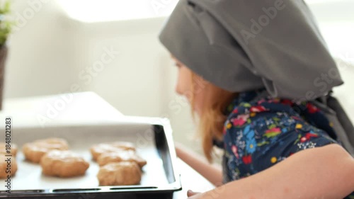 Little girl baker holding in hands baking sheet with homemade cookies