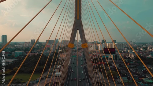 symmetric modern cable-stayed Rama VIII bridge over Chao Phraya river in Bangkok, perspective of contemporary suspension urban span connecting city skyline across Thai waterway, aerial drone view 4k