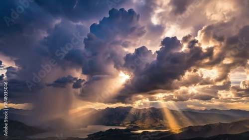 Dramatic sun rays breaking through dark storm clouds over mountains