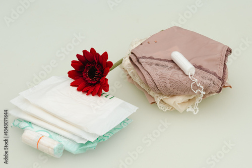 Quadro su tela Feminine still life with menstrual products, folded lingerie and a red flower, symbolizing menstruation, body care, self-care, and a calm, respectful approach to women’s health