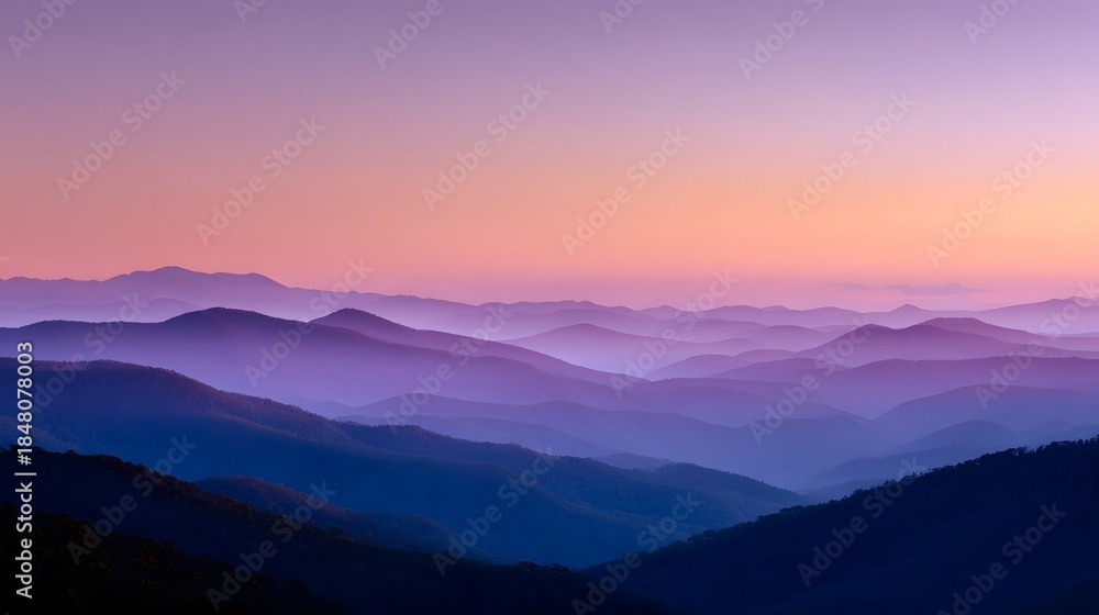 Fototapeta premium Layered mountain ridges fade into a pastel-colored twilight sky
