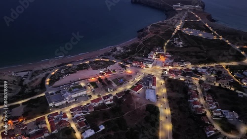 Evening aerial view of Sagres portugal coastline and city lights reflecting at night from above