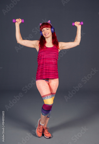 Beautiful happy fitness woman workout purple dumbbells portrait