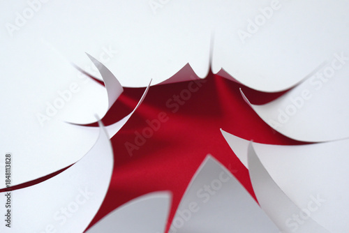 Coups de cutter sur feuille blanche et rouge derrière