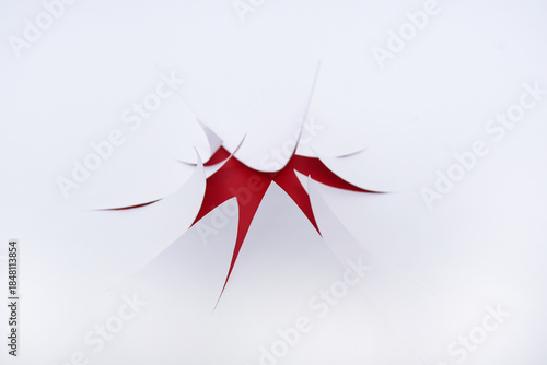 Coups de cutter sur feuille blanche et rouge derrière