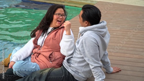 Couple sharing a playful moment and laughing by a fountain