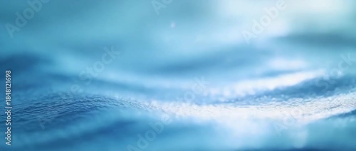 Close-up of blue water waves with sunlight reflections, showcasing gentle motion and shimmering surface texture, evoking serenity and natural aquatic calm.