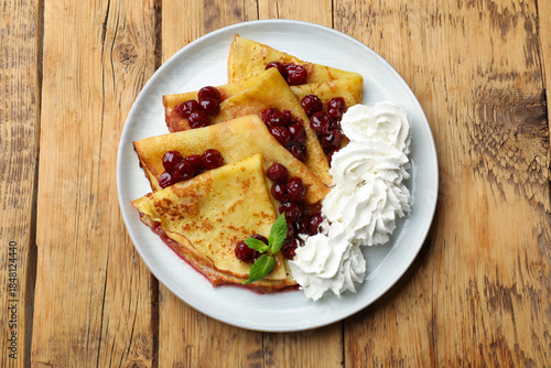 Fényképezés Tasty crepes with cherries, whipped cream and mint on wooden table, top view