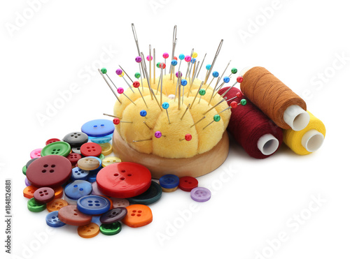 Yellow pincushion with pins, needles, buttons and coils of threads isolated on white