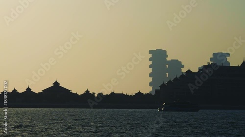 Silhouette of Dubai Palm Islands buildings at sunset with modern architecture of Atlantis Royal and calm sea