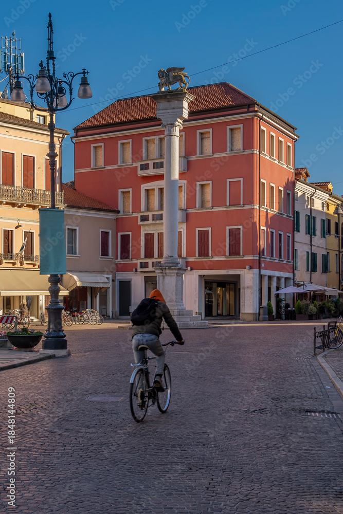 Obraz premium A cyclist passes through Piazza Vittorio Emanuele II, Rovigo, Italy