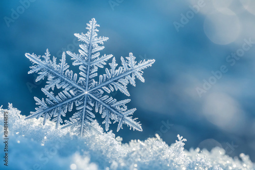 Macro close-up of a delicate snowflake resting on fresh snow, symbolizing Christmas, winter beauty, and the magic of the holiday season with a soft blue background.