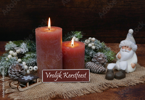 Kerstkaart: Kerstgroeten in het Nederlands met bruine kaarsen, kerstversiering, een kerstman met besneeuwde dennentakken. Vrolijk Kerstfeest en een Gelukkig Nieuwjaar!