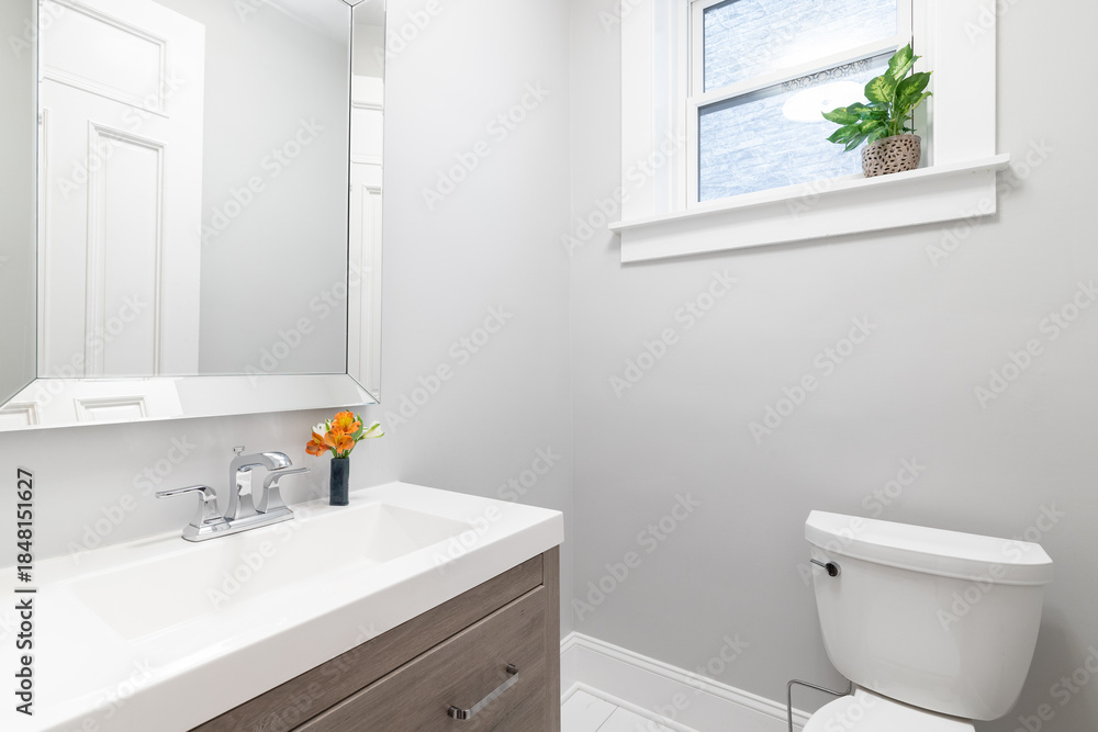 Obraz premium A clean and modern bathroom featuring a wood vanity with a sink, faucet, and mirror, adjacent to a toilet.