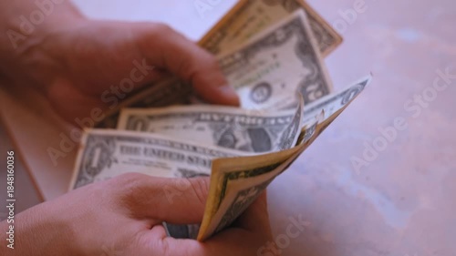 Close up view of male hands counting one dollar bills, a representation of financial planning, calculating expenses, savings management, and the concept of personal income and payment
