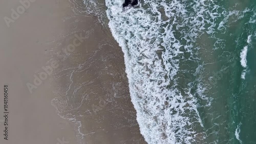 Ocean waves breaking on a sandy beach below a cloudy sky in ferrol, galicia