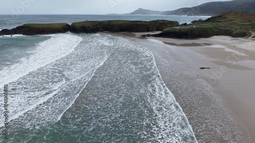 Ocean waves breaking on a sandy beach below a cloudy sky in ferrol, galicia