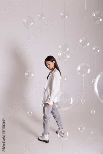 A woman with black hair wakes up in the morning in a white blanket and catches the rays of the sun. The portrait is creative, with brown eyes. High quality photo