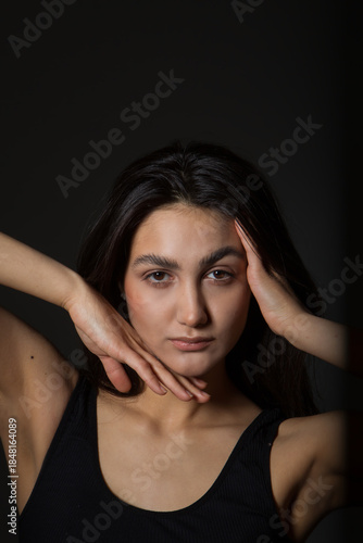 A woman with black hair wakes up in the morning in a white blanket and catches the rays of the sun. The portrait is creative, with brown eyes. High quality photo