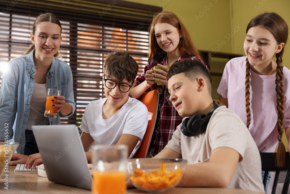 Fototapeta premium Teenagers playing online game on computer and having snacks at home