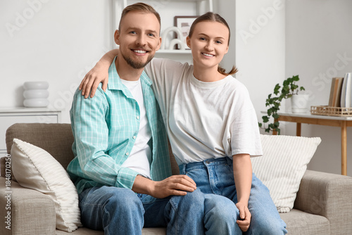 Happy young couple hugging on sofa at home
