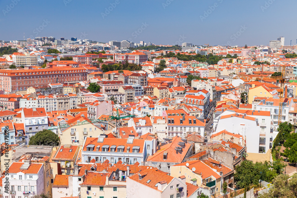 Obraz premium Panoramic aerial view of a sunlit Lisbon with dense red tiled roofs, colorful facades