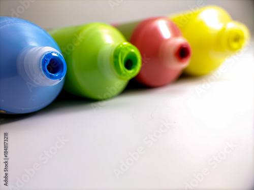 close up paint tube nozzles are arranged in a row on a white surface. 