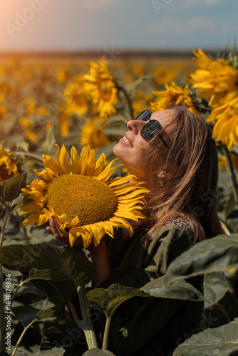 A girl in a pink skirt and a white T-shirt walks through a field of blooming yellow sunflowers. A woman dances, rejoices, smiles, enjoys life, warmth, summer, the sun. High quality FullHD footage